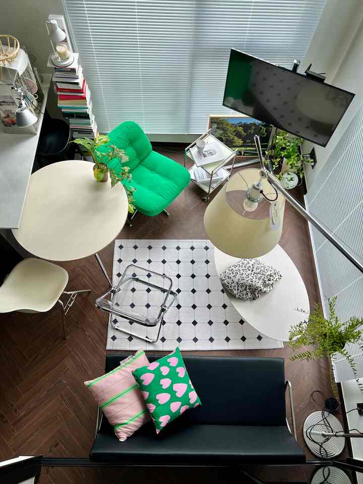 ナチュラルでモダンな色調のリビング、中央に黒いソファと緑色のアームチェアが配置された印象的な空間