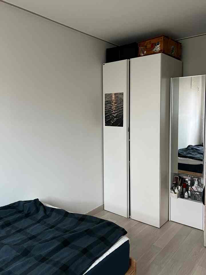 白い壁と木目調の床、青い寝具とクローゼットが配置されたコンパクトな寝室玄関スペース