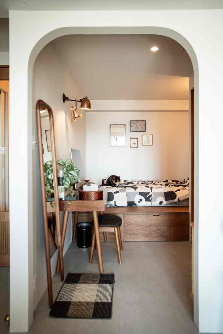 ナチュラルカラーの寝室、コンパクトなマットレスベッドとワークスペース、ペットの猫と過ごす雰囲気のあるインテリア