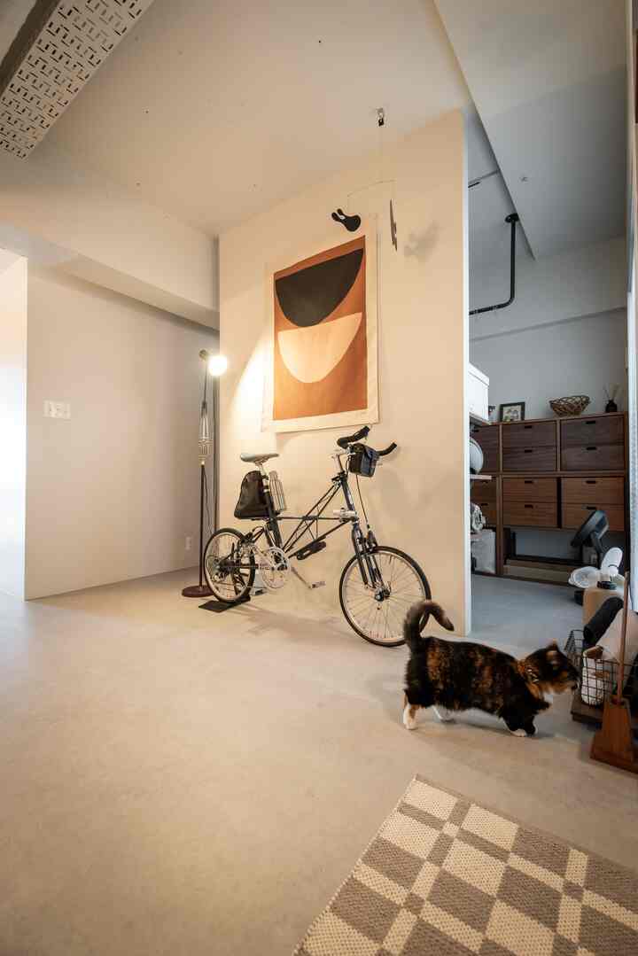 ブラウンとホワイトの色調の玄関とワークスペース、自転車と猫がいる印象的な空間