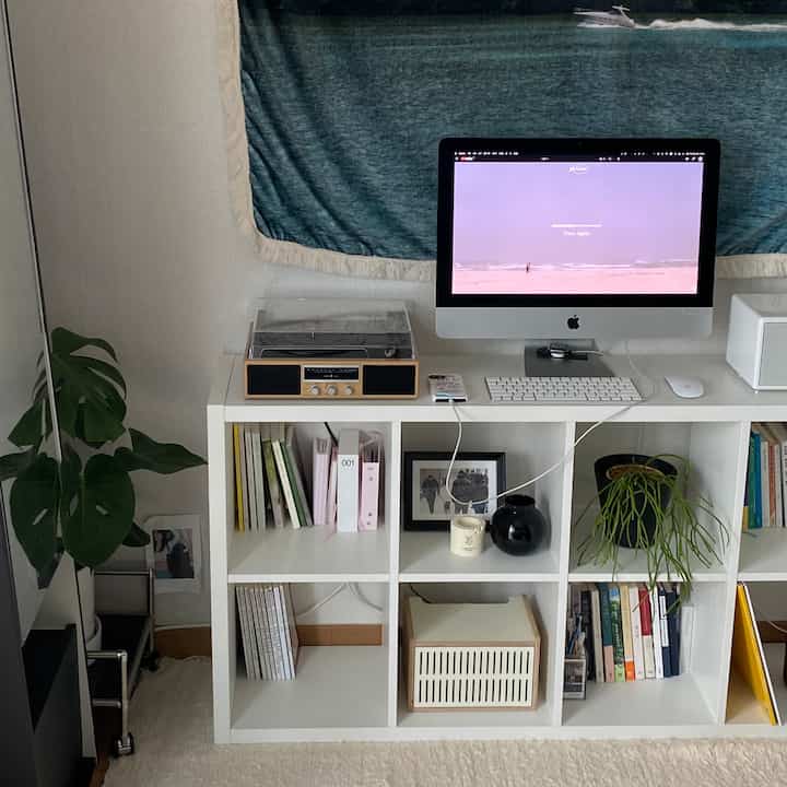 白とナチュラルカラーの書斎、白い本棚と植物が配置されたミッドセンチュリーモダンで印象的な空間