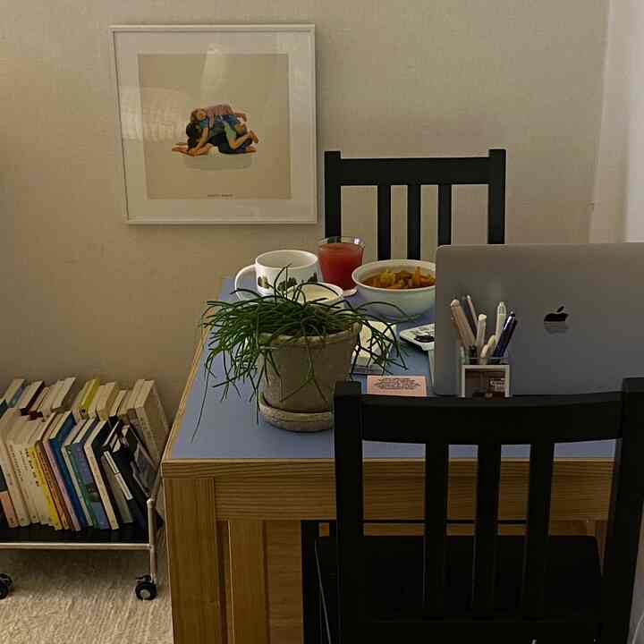 ナチュラルな木目調とブルーの色調のホームオフィス、デスクの上に植物とパソコン、本が配置された雰囲気のある作業空間