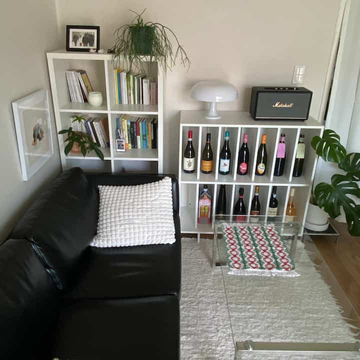 ホワイトとブラックの調和のとれたリビング、レザーソファとワインラック、書棚、植物が心地よい雰囲気を演出するインテリア