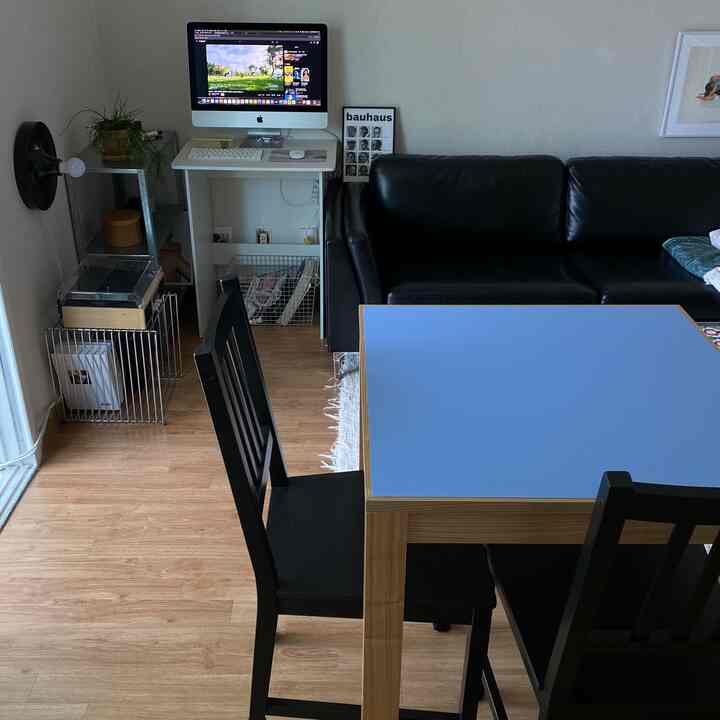 黒のレザーソファと青いダイニングテーブルが配置されたモダンでナチュラルな雰囲気のリビングとホームオフィス