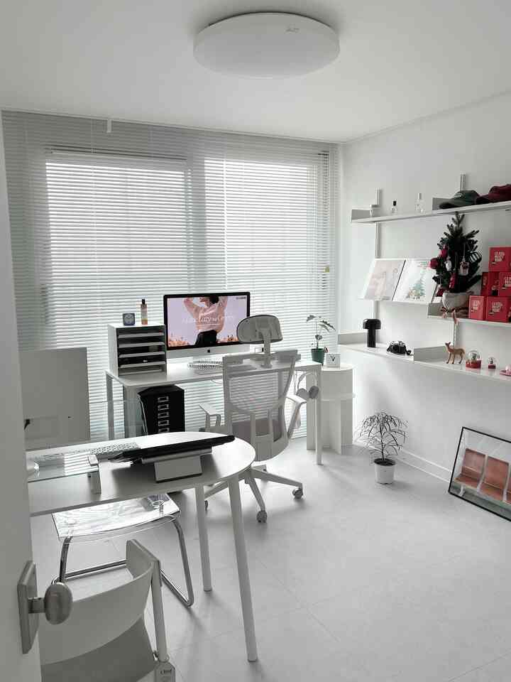 白を基調とした明るいホームオフィス、パソコンデスクとオフィスチェア、壁掛け棚が配置されたモダンなインテリア