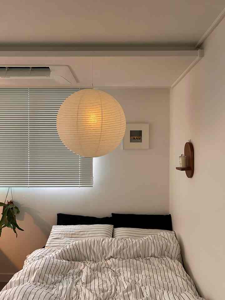 ホワイトと木目調の寝室、和紙のペンダントライトと木製ブラインド、植物が配置された清潔感と自然な雰囲気のあるインテリア