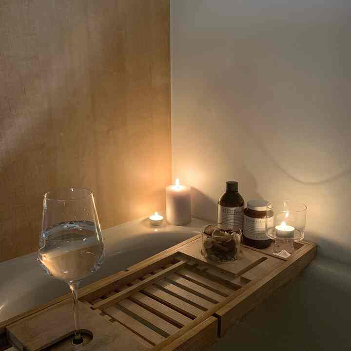 ナチュラルカラーと木目調のバスルーム、木製トレーとキャンドルが配置された落ち着いたリラックス空間