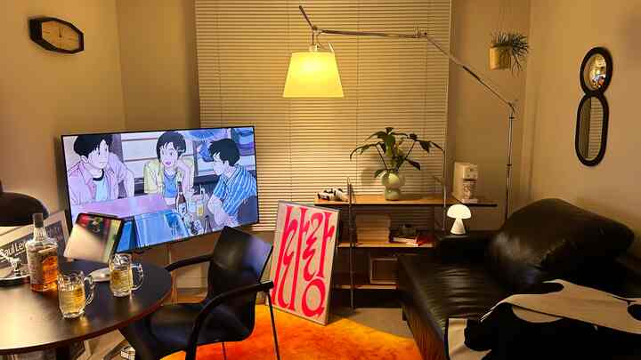 温かみのあるオレンジのラグと黒いソファが置かれたリビング、丸テーブルと照明が心地よいホームバーの雰囲気を演出しています。