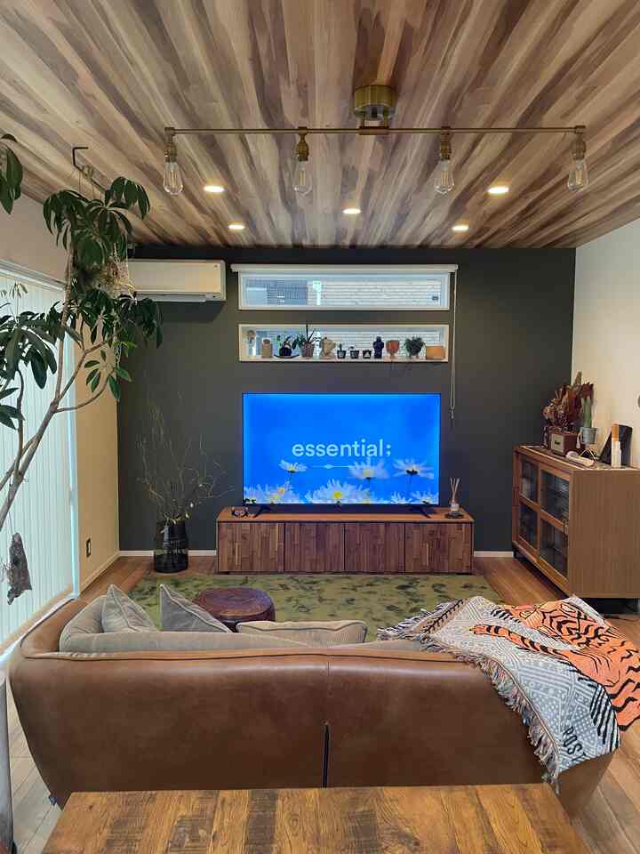 カーキ色の壁とブラウンのレザーソファが印象的なナチュラルモダンなリビング空間