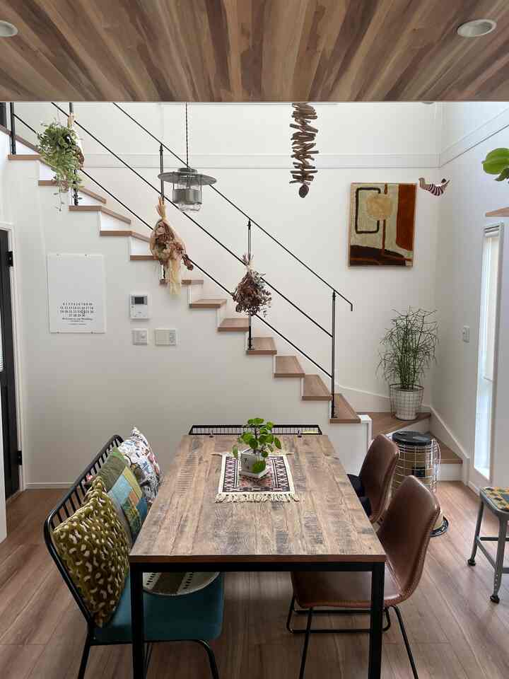 ナチュラルなブラウンとホワイトのトーンが印象的なダイニング、木製のダイニングテーブルとベンチ、ブラウンのチェアが配置された雰囲気のあるインテリア。