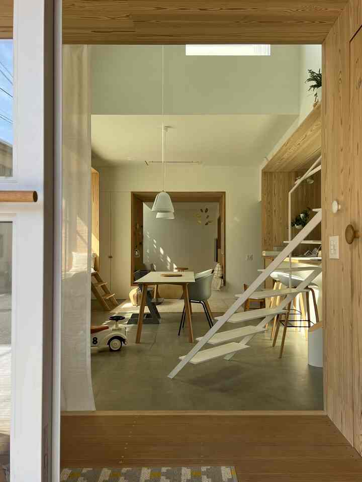 白と木目調が調和した玄関から見たナチュラルでミニマルな4人用ダイニングルームの印象的な空間