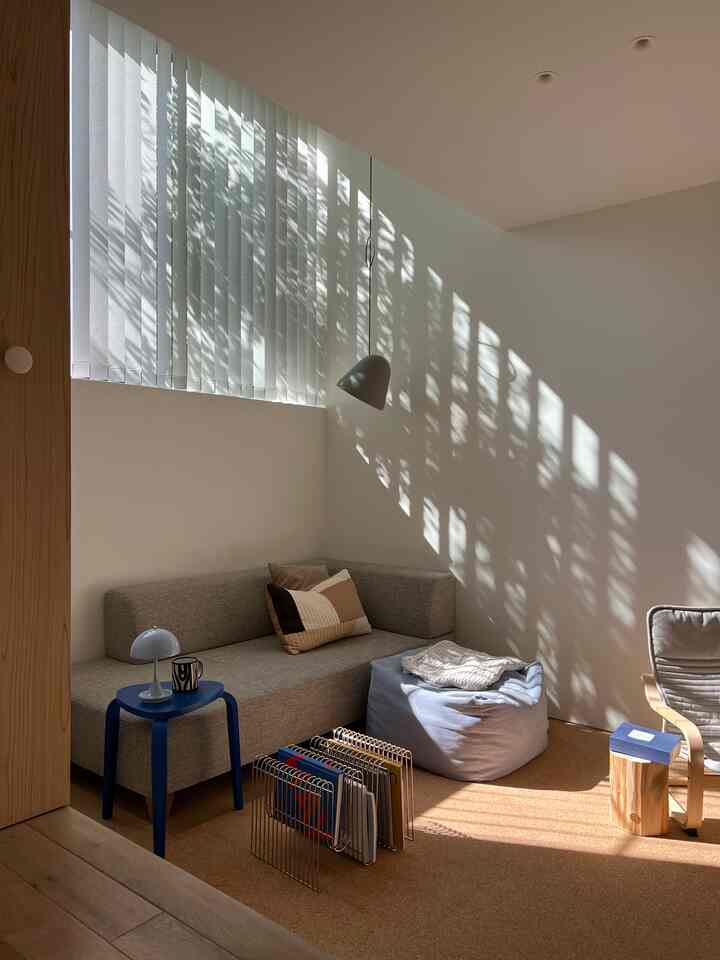 ナチュラルトーンのリビング、ベージュのソファとブルースツール、ビーンバッグが配置された落ち着いた雰囲気の空間