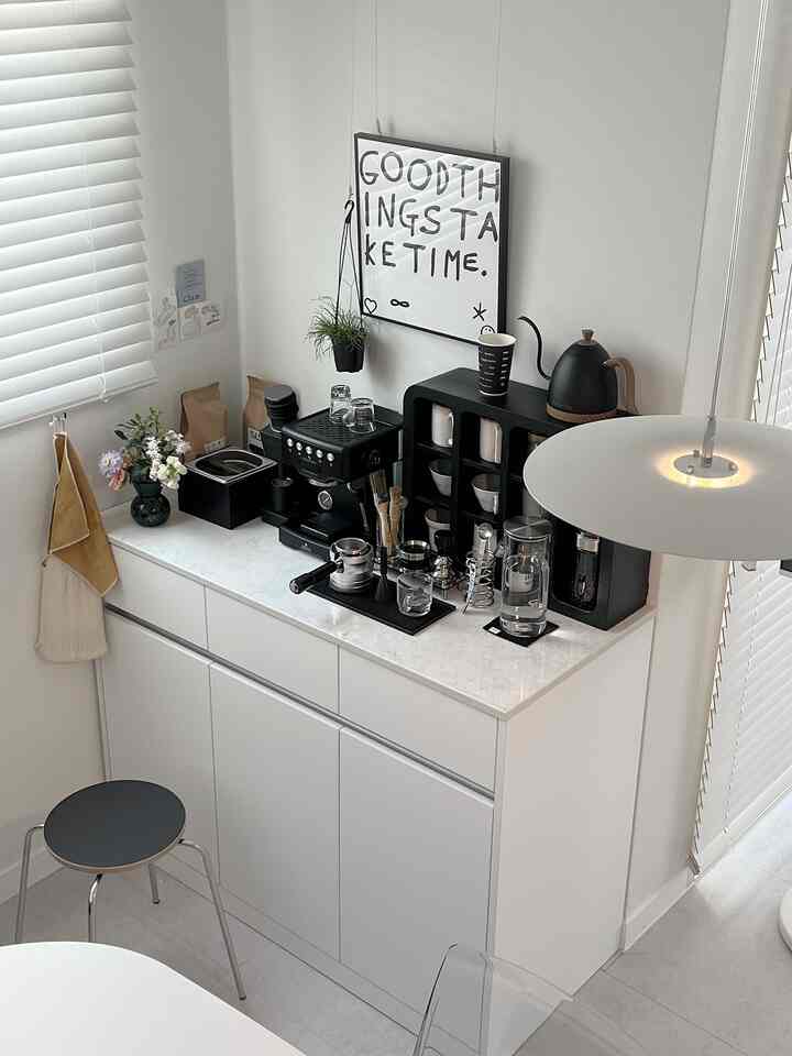 白と黒のトーンが印象的なキッチンスペース、コーヒーマシンと収納棚が配置されたモダンなおうちカフェ