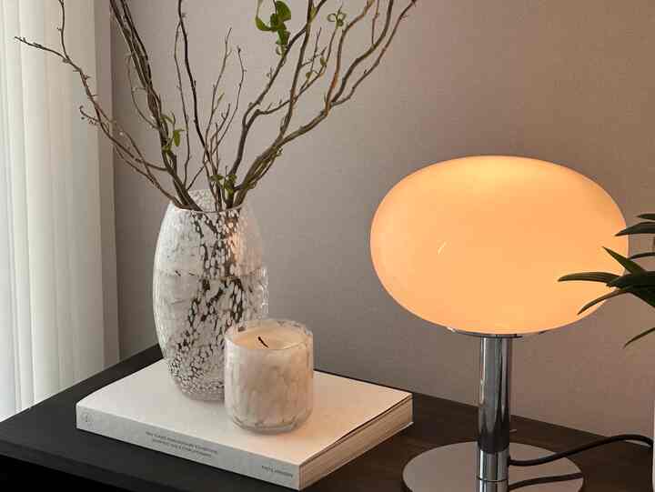 暖かい光が灯る木目調のテーブルの上に、透明な花瓶とキャンドルが配置された雰囲気のあるインテリア