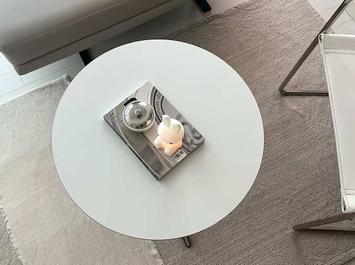 ナチュラルカラーとホワイトトーンのリビング、丸いコーヒーテーブルとアームチェアが配置された印象的な空間