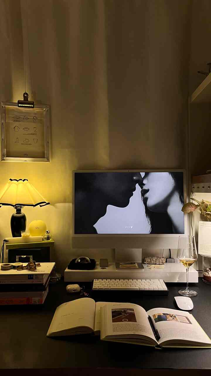 アイボリーとブラックのトーンが調和したホームオフィス空間、アップルのiMacとワイングラス、机に開いた日記帳が配置された落ち着いた作業空間