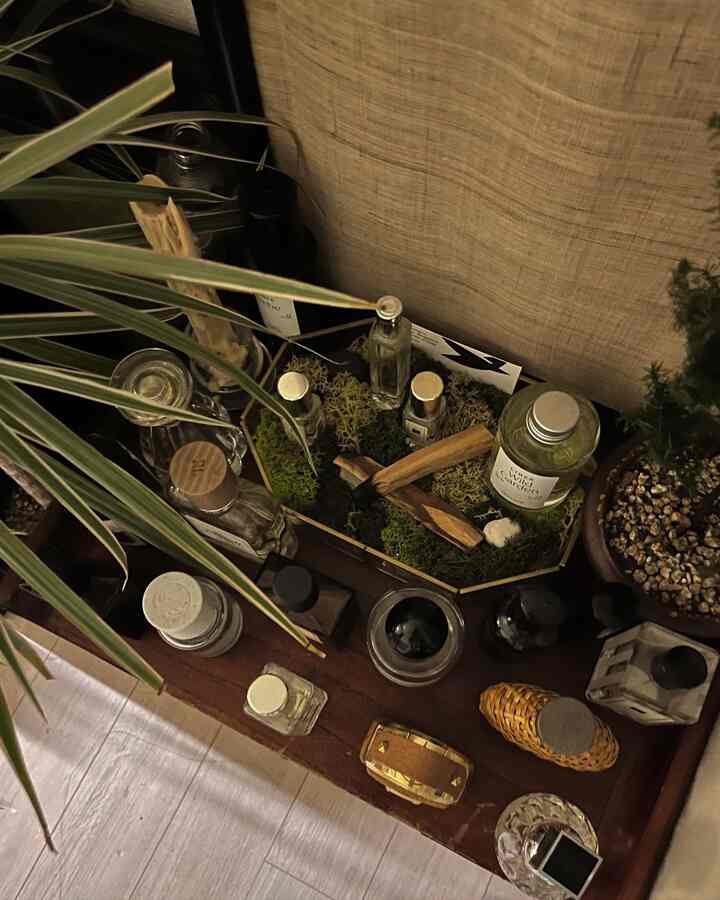 ゴールドトレイに香水とディフューザーの瓶が置かれたナチュラルカラーのインテリア空間