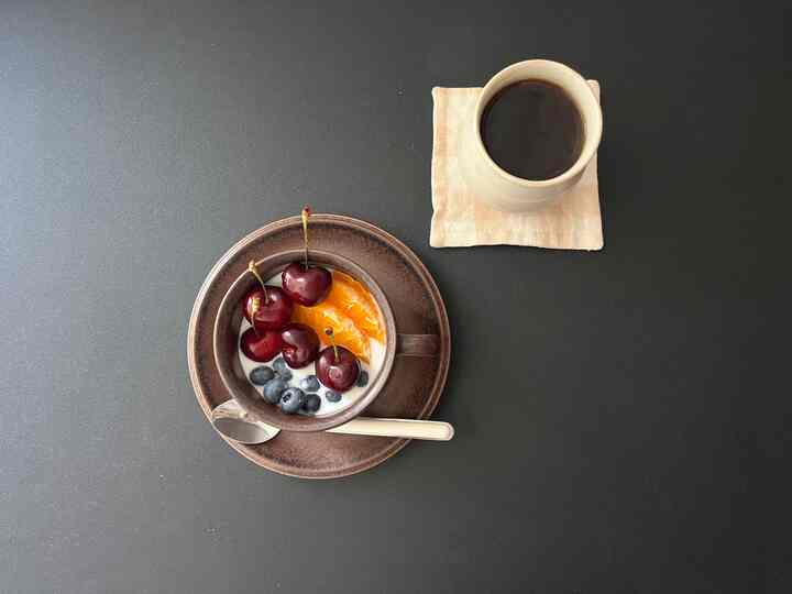 ブラウンのコーヒーカップと果物が盛られた器が置かれたブラックテーブルの雰囲気のあるおうちカフェ空間