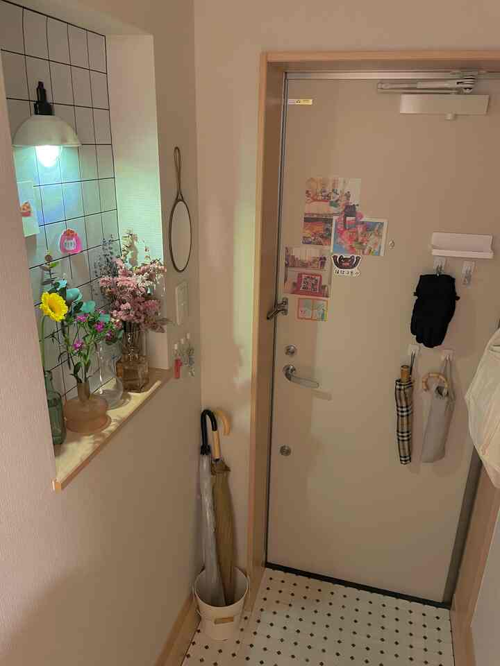 ホワイトカラーの小さな玄関、レトロなタイル床と傘収納が整った空間