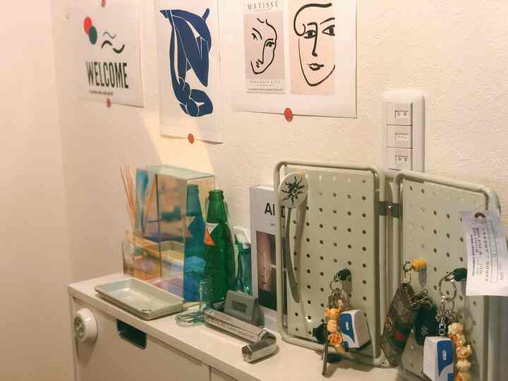 白を基調とした玄関スペース、ペグボードのキー収納と装飾的なオブジェが配置されたシンプルなインテリア