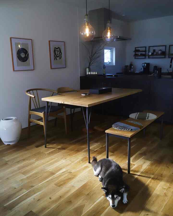 ナチュラルな木目調のダイニングルーム、ペンダントライトが配置され、床には犬が伏せている雰囲気のある空間
