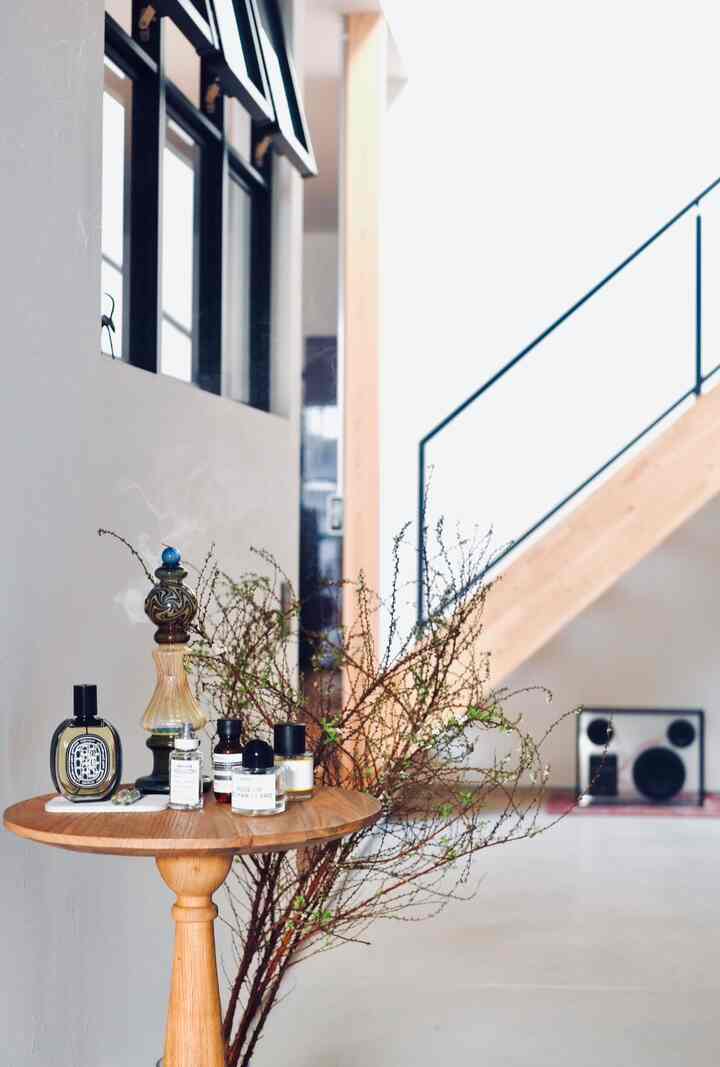 ナチュラルな木目調の玄関、サイドテーブルと植物の枝が配置された雰囲気のあるインテリア