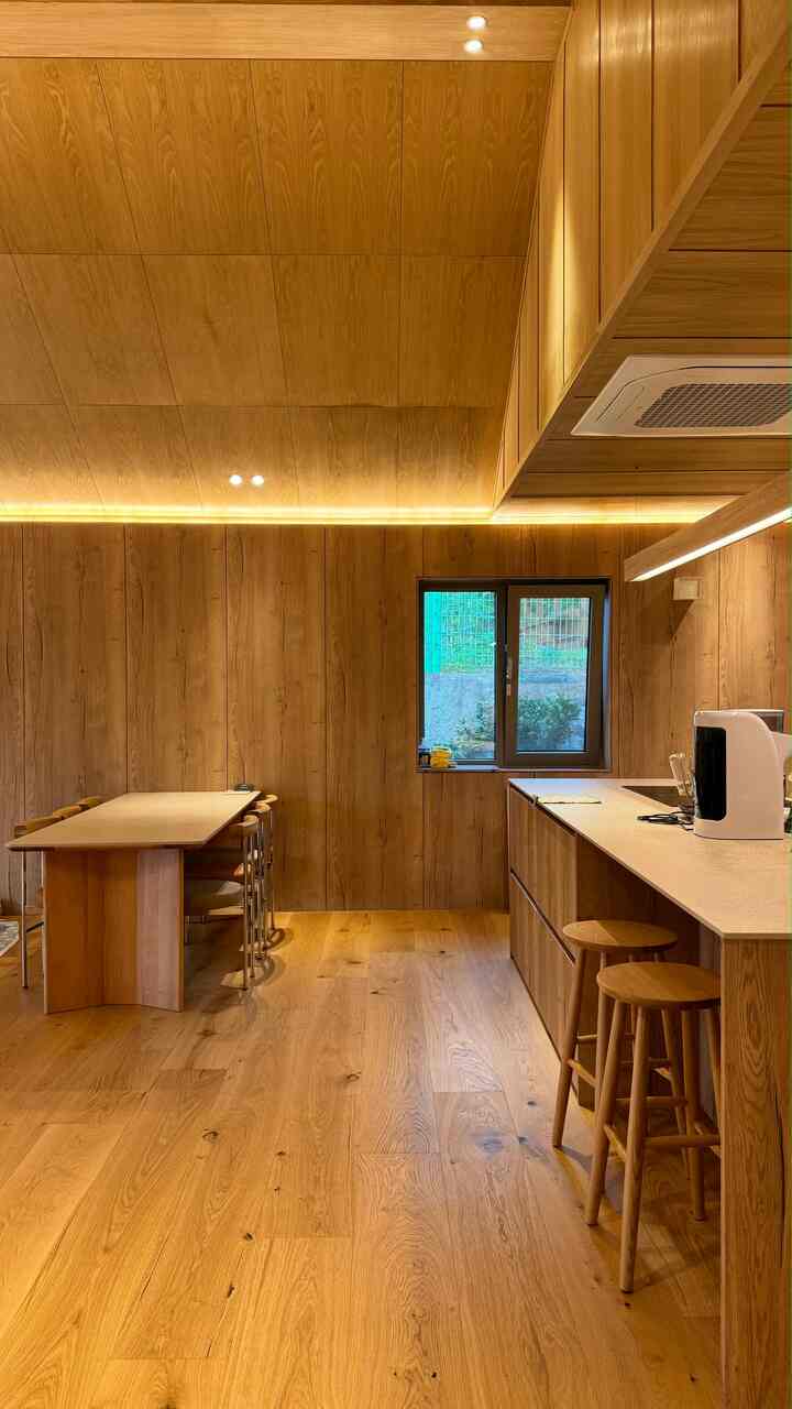 温かみのある木目調のキッチン、無垢材のアイランドとスツールが配置された雰囲気のあるインテリア