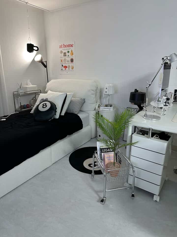 白と黒のトーンで統一された寝室、シンプルモダンなスタイルに植物とホームオフィスのデスクが配置された洗練されたインテリア