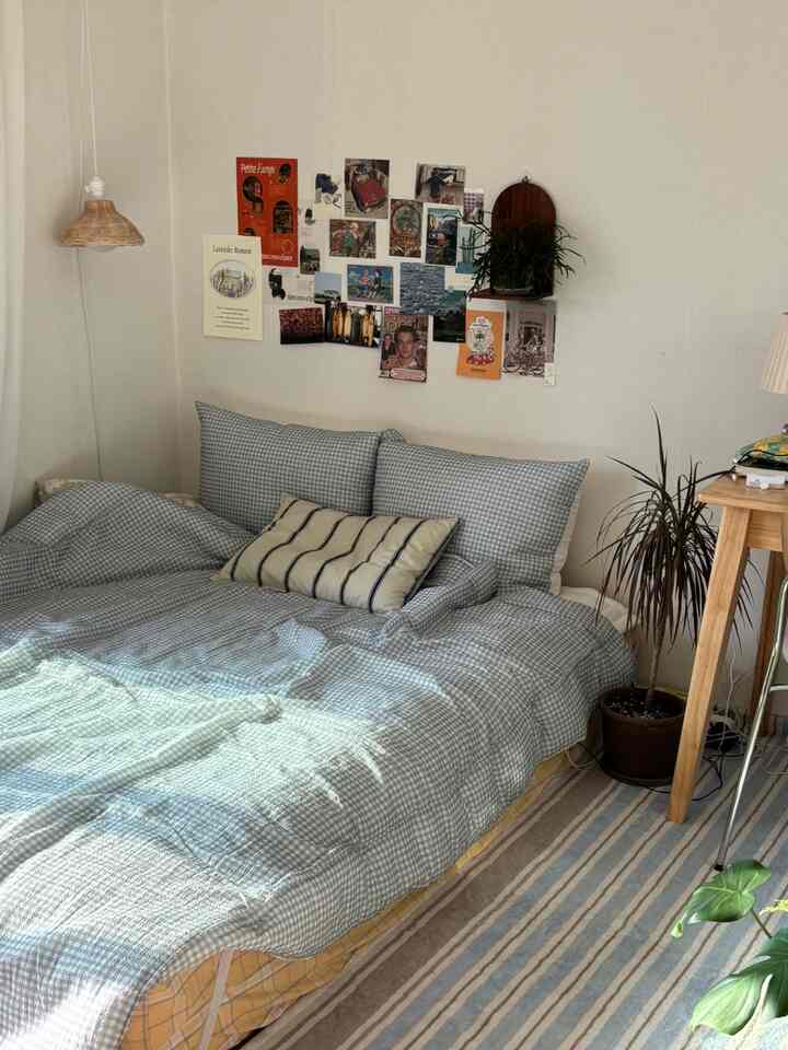 ライトグレーの寝具がある寝室、壁にレトロなポスターと植物が配置された雰囲気のあるインテリア