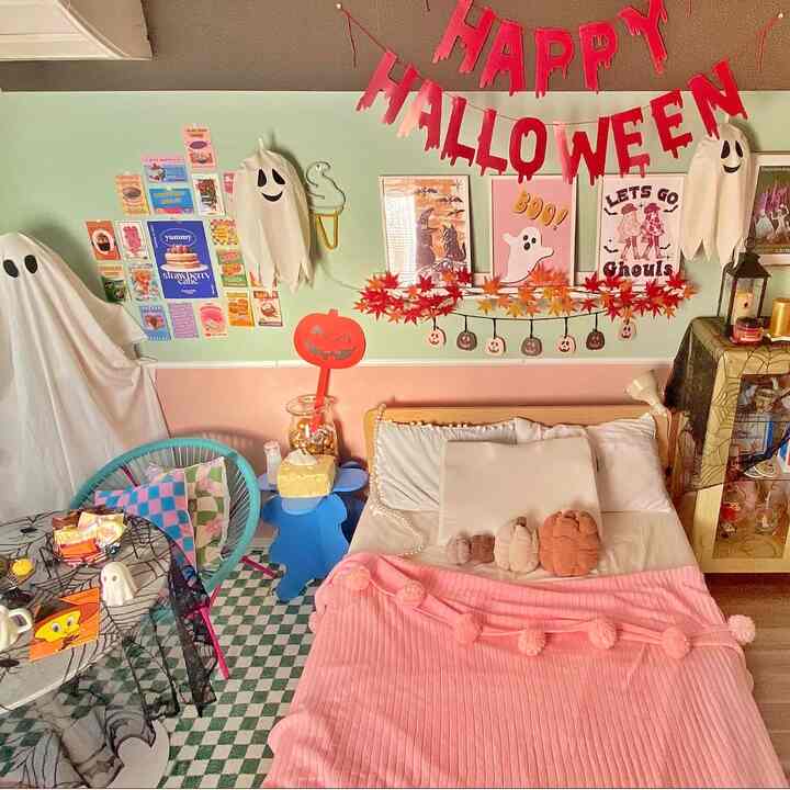 ピンクと白の色調の寝室、DIYのハロウィンおばけランプとカラフルな壁の装飾が配置された雰囲気のあるインテリア