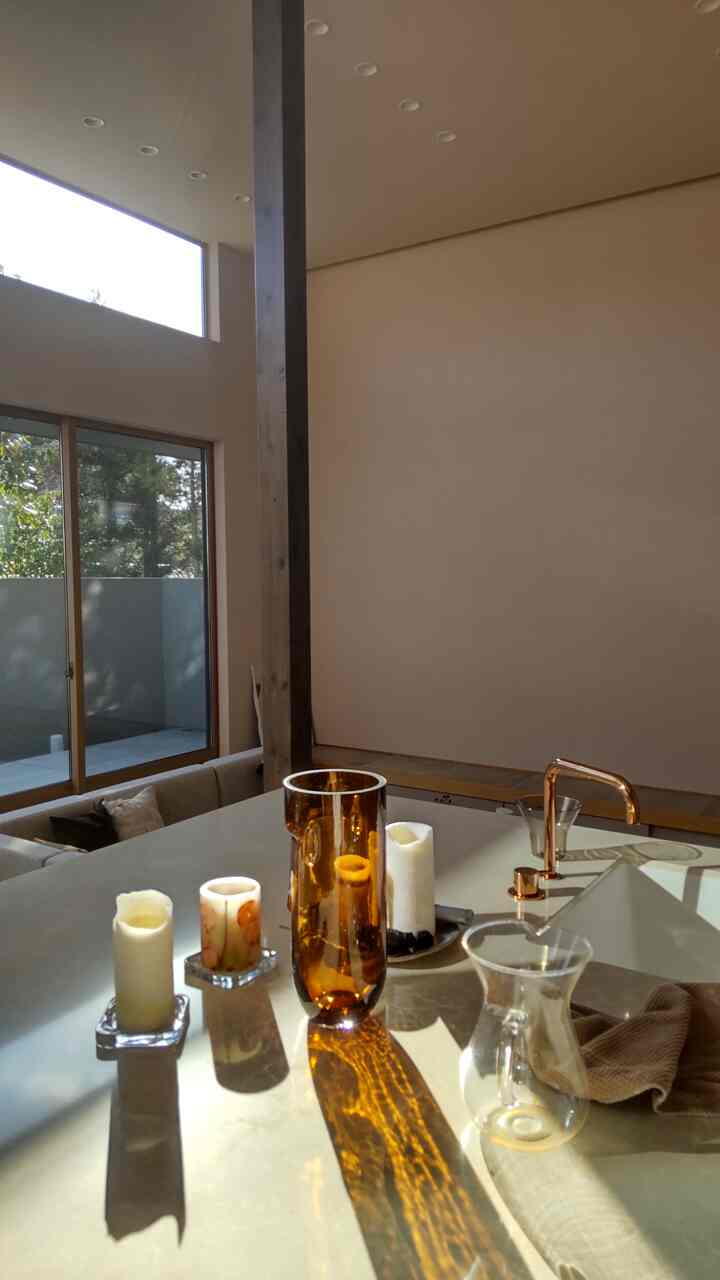 暖かいベージュと木目調が融合したダイニングルーム、琥珀色のガラスとキャンドルが置かれた雰囲気のある空間