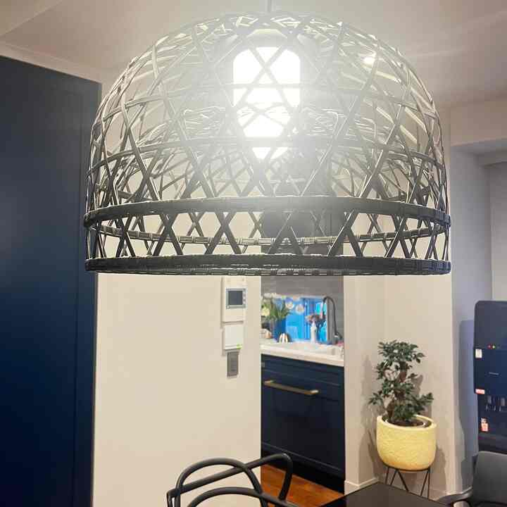 白い壁とネイビーカラーのキッチンキャビネットが配置されたダイニング、ペンダントライトとダイニングチェアがあるモダンな空間