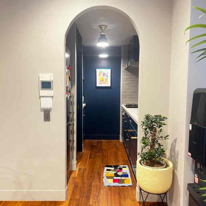 ネイビーと木目調が調和したアールデコ風キッチン、特徴的なアーチ状の入口があるモダンな空間