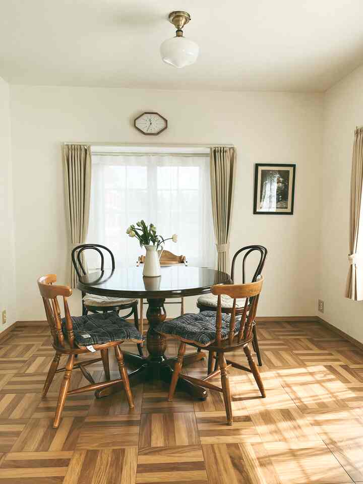 明るい白い壁と木目の床、円形のダイニングテーブルと椅子が配置された3人家族向けのナチュラルなダイニング