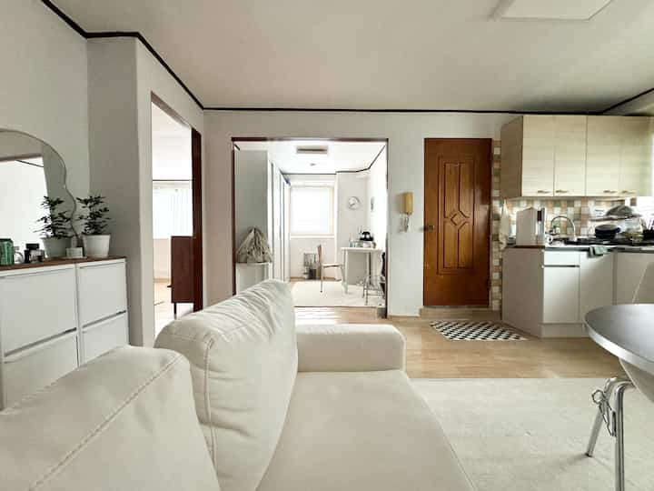 白と木目調が調和したコンパクトなワンルームのリビングとキッチン、シンプルなデザインの空間