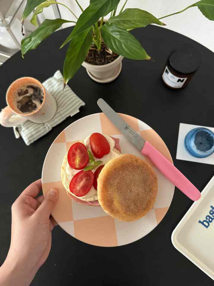 黒い丸テーブルの上にピンクのナイフとチェック柄の皿が置かれたおうちカフェの空間