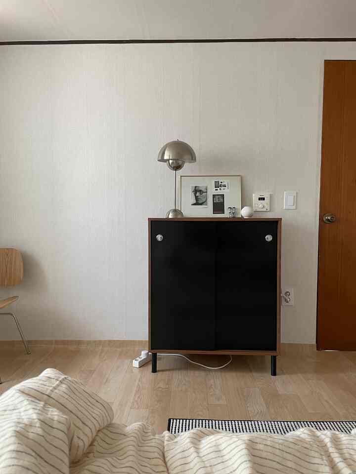 ナチュラルな木目調とブラックのキャビネットが配置されたシンプルで落ち着いたリビングインテリア