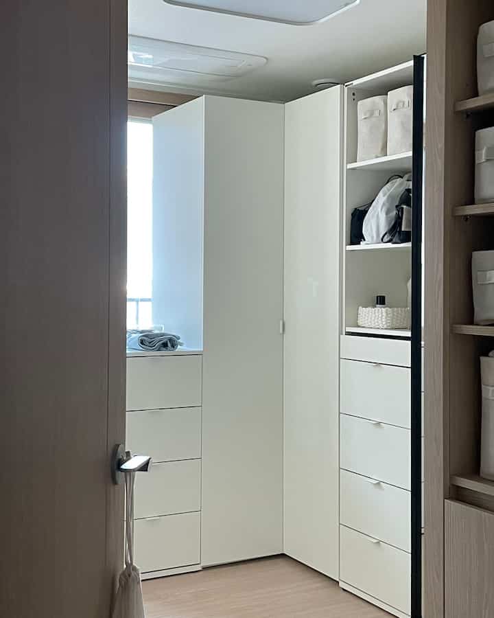 白とナチュラルカラーの調和が美しい、コーナー収納が特徴的なウォークインクローゼットの室内