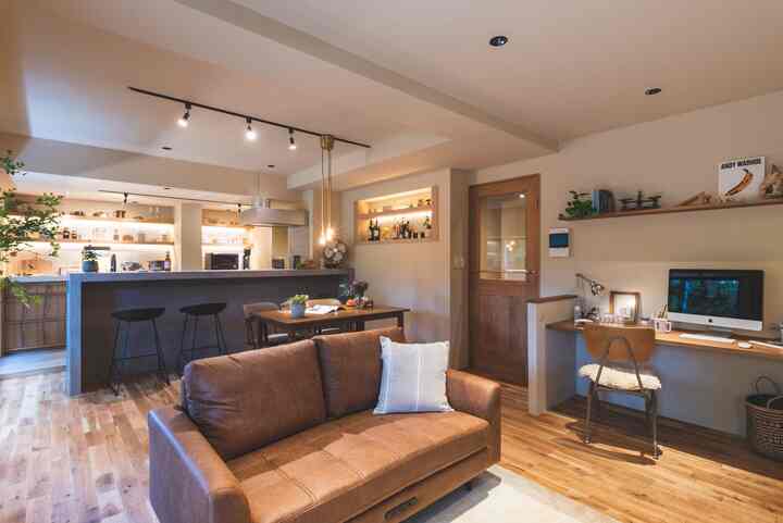 ベージュとブラウンのトーンのリビング、ソファとホームオフィスデスク、ダイニングテーブルが調和した温かみのある印象的な空間