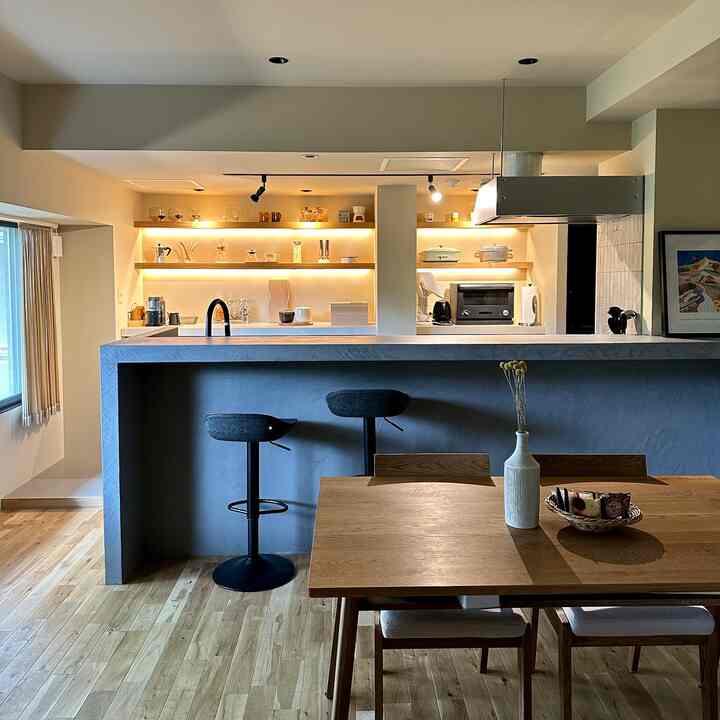 木目調のモダンなキッチン空間、カウンタースツールとダイニングテーブルが配置された雰囲気のあるおうちカフェ