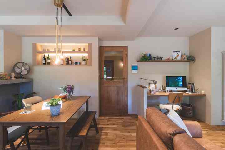 ベージュとウッドトーンの自然なリビング＆ダイニングルーム、中央にダイニングテーブル、右にホームオフィスが配置された居心地の良い空間