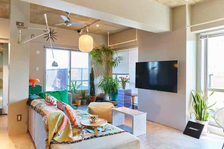 ベージュと木目調のリビング、大きな窓と多様な植物が配置され、居心地よく自然な雰囲気のインテリア