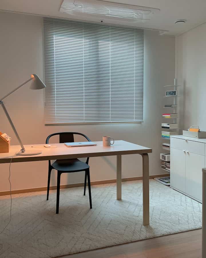 白と黒のトーンのホームオフィス、机と椅子、ブラインドが配置された清潔感のある作業空間