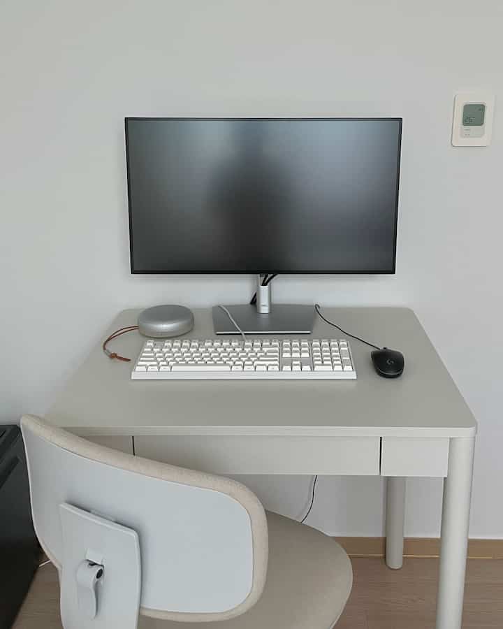 グレーと白を基調としたコンパクトなワークスペース、モニターと小さなデスク、オフィスチェアが配置されたシンプルでモダンなインテリア