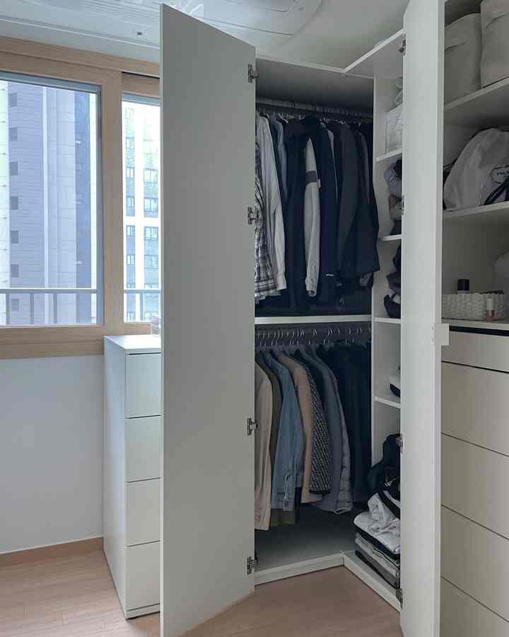 ホワイトとナチュラルウッド調の寝室コーナーに配置されたL字型のホワイトワードローブが特徴的な、すっきりとした収納効率の良い空間