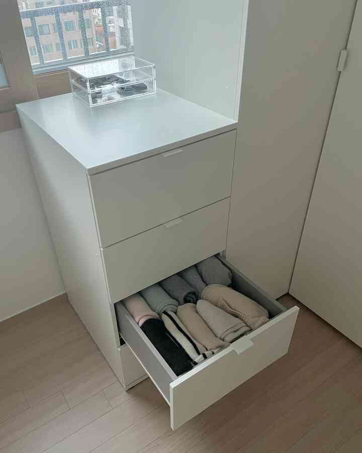 白を基調としたミニマルなデザインのチェストが窓際に配置され、明るく清潔感のある空間