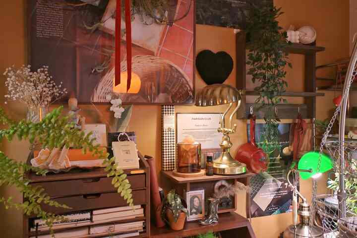 ブラウンとゴールドが調和するナチュラルスタイルの壁面装飾空間、多様な植物とポスターが配置された雰囲気のあるインテリア