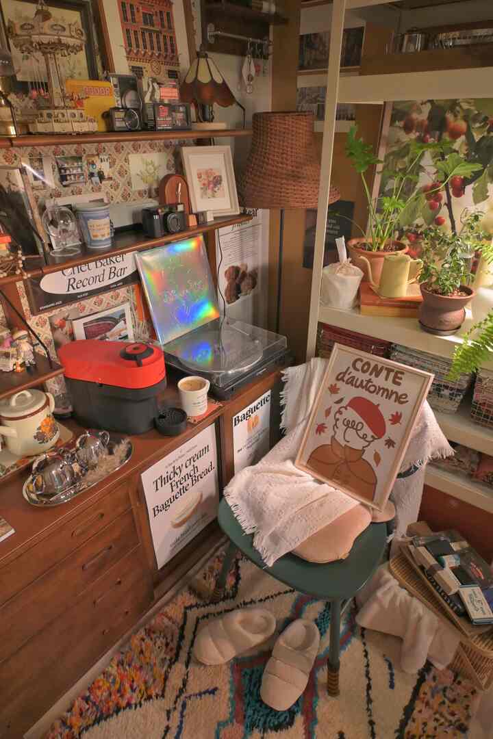 温かみのある木目調とヴィンテージ小物が配置された居心地の良いリビング、ポスターと植物が調和した自然な雰囲気のインテリア