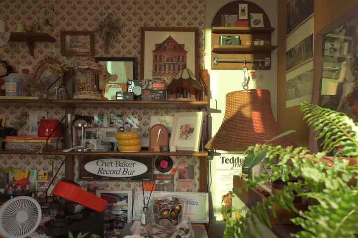 ヴィンテージ風のナチュラルな色調のカフェスタイル空間、壁を飾る額縁やラタンの照明、植物が配置された暖かみのあるおうちカフェ