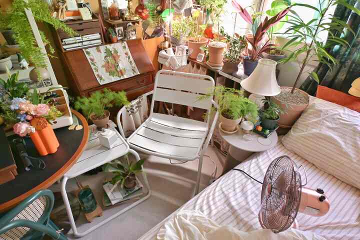 ナチュラルな色調の小さな寝室、アウトドアのメタルチェアと植物が配置されたリラックス空間